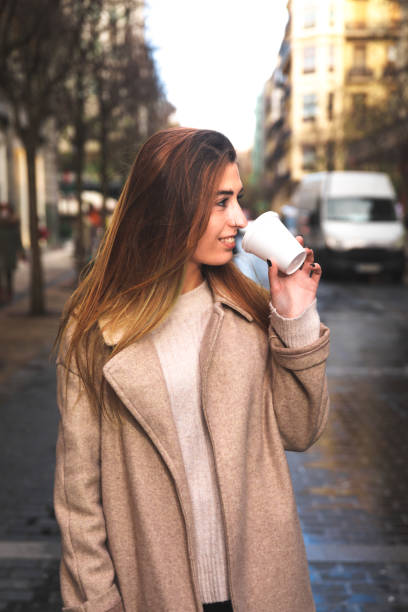istock Young caucasian woman talking by phone while drinking a coffee in a plastic cup at Donostia-San Sebastian downtown; Basque Country. 1298380322