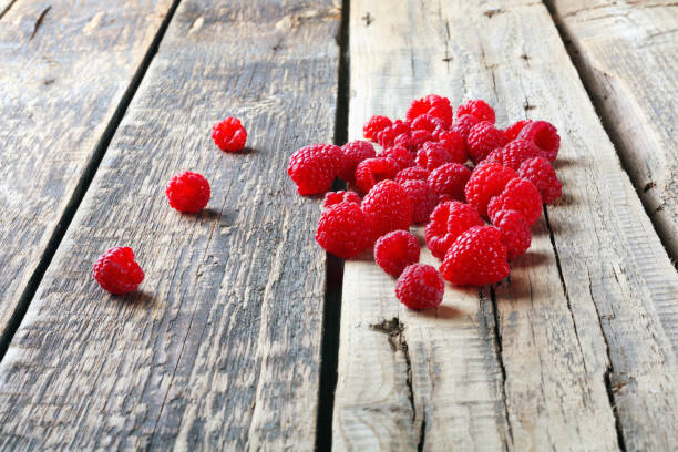 istock Fresh juicy tasty raspberries scattered on  table 1298382404