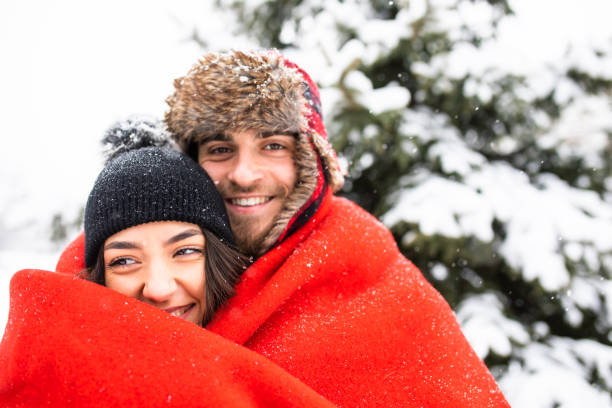 A happy couple under a blanket on a snowy day stock photo