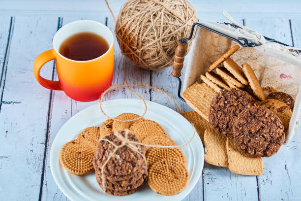istock Assorted biscuits in plate and basket and a cup on blue table 1298387239
