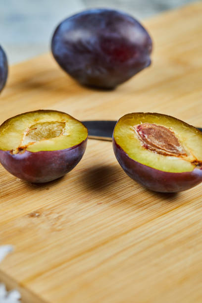 Whole and half cuts of plum on wooden board
