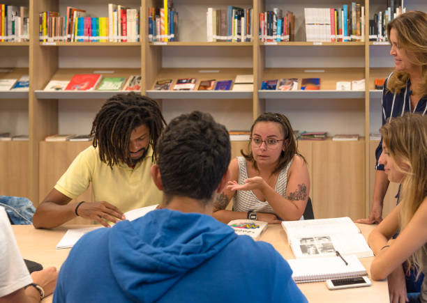 istock Table in library, with young Brazilian university students, studying and debating ideas 1298388951