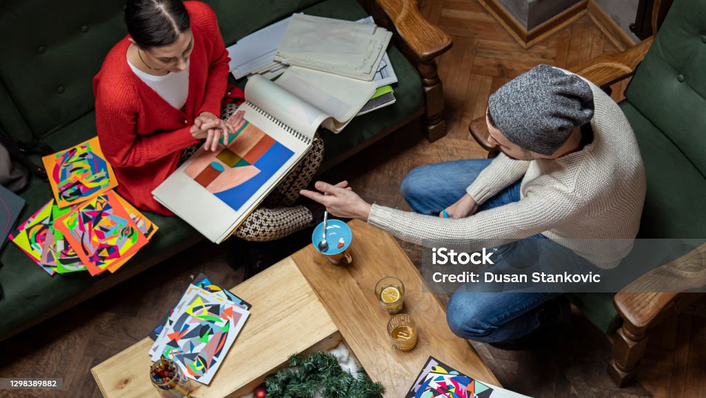 Two freelance artists, designers, working in coffee shop Photo of two artist, man and woman, working in coffee shop on their design. Art Stock Photo