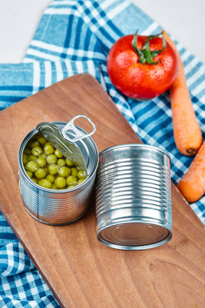 istock Two cans of boiled green peas, vegetables and tablecloth on a white background 1298392366