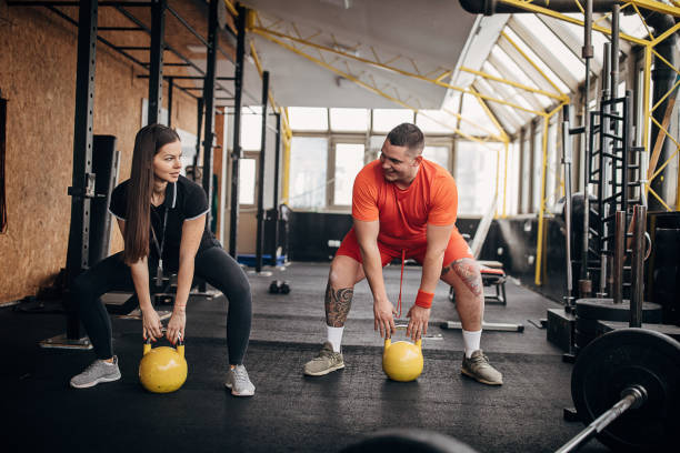 istock Female personal trainer showing her male trainee right way to exercise with weights 1298393765