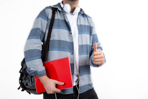 istock Casual wear content young man posing with backpack and textbook. Student and education concept, isolated on white background. 1298395239