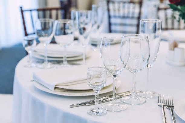 istock Fancy table set for dinner with napkin glasses in restaurant, luxury interior background. Wedding elegant banquet decoration and items for food arranged by catering service on white tablecloth table 1298400934