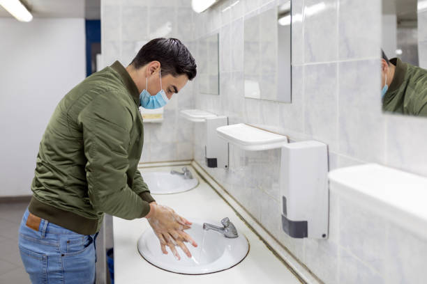 istock Man washing his hands to avoid diseases like coronavirus Man with a face mask washes his hands in a public bathroom 1298401263