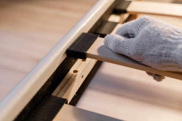 istock Male worker's hand in glove assembling bed, connecting slats to bed frame 1298402628