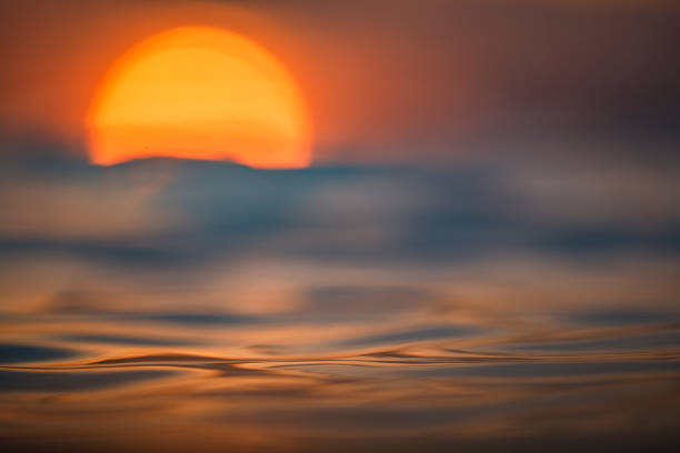 istock Sun rising over the ocean with textured golden water surface 1298403005