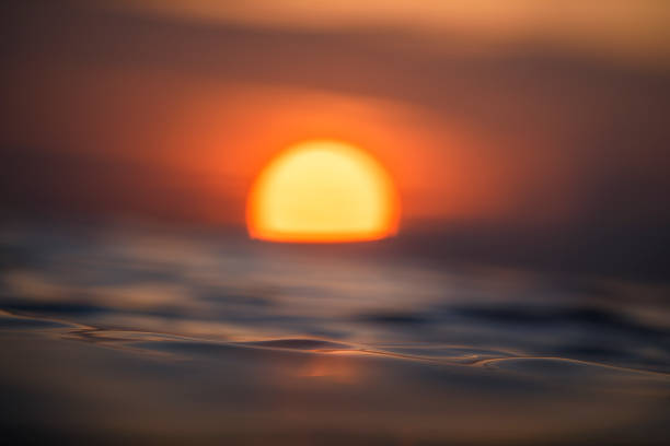 istock Sun rising over the ocean with textured golden water surface 1298403182