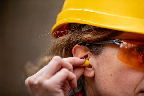 primer plano de la mujer adulta trabajadora que inserta protectores de oído - orejeras fotografías e imágenes de stock