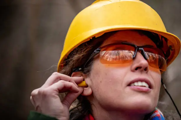Adult Woman Forester Inserting Ear Protectors.