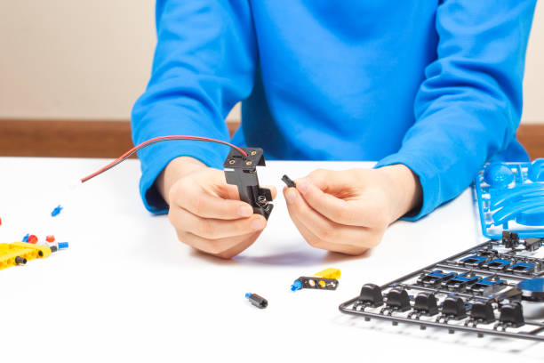istock Child hands making robot car. Robotic, learning, technology, stem education for children background 1298405483