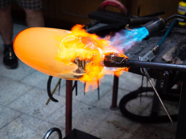 istock Artist glass blowing process. The glassblower master create 1298406384