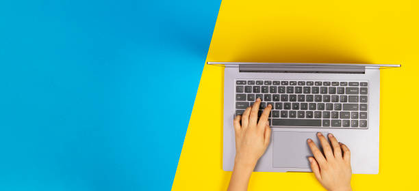 istock Kid hands typing on laptop computer keyboard, top view, yellow and blue background 1298406930