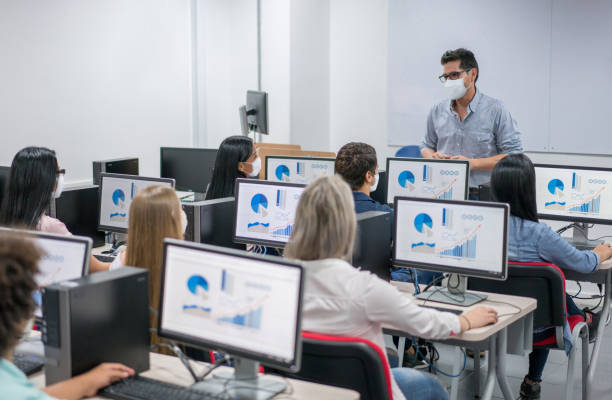 istock Teacher wearing a facemask while giving an IT class at college 1298407387