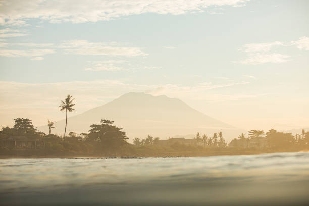 Golden sky over a volcano, with palm trees photographed from the ocean