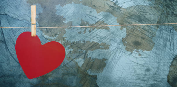 Heart hanging on line against rusty weathered wall
