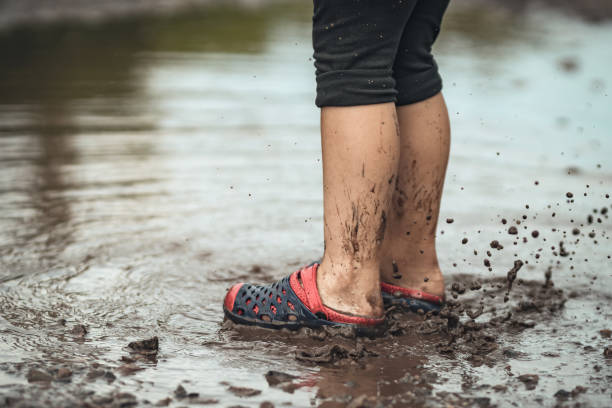 istock Children's feet walking in a muddy puddle after the rain 1298411861
