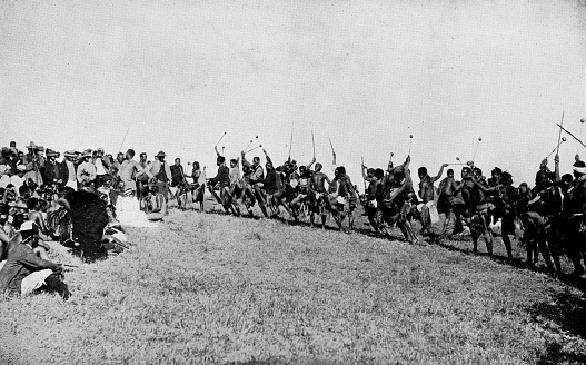 AmaZulu men performing a Indlamu (Traditional African Zulu dance) during at wedding at a kraal (village) in the Kingdom of Zululand, South Africa. Vintage photo etching circa 19th century. It was absorbed into the British Colony of Natal in 1897, and then the Union of South Africa in 1910.