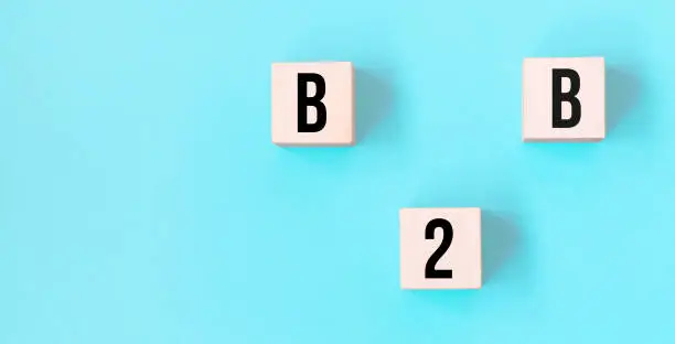 Photo of Concept word B2B - business to business on cubes on a beautiful blue background. Business concept. Copy space.