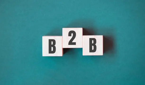 Photo of Concept word B2B - business to business on cubes on a beautiful green background. Business concept. Copy space.