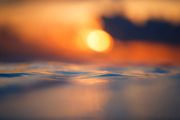 istock Sun rising over the ocean with textured golden water surface 1298417788