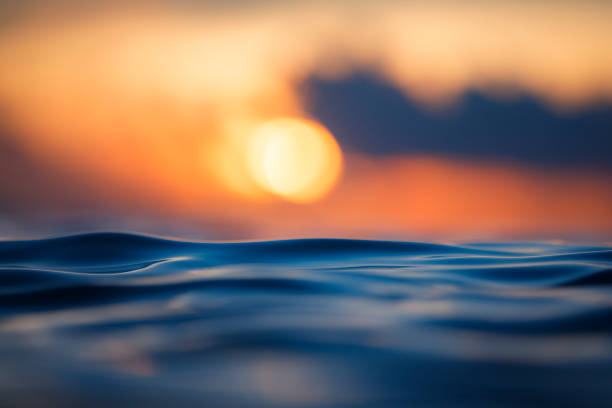 Sun rising over the ocean with textured golden water surface