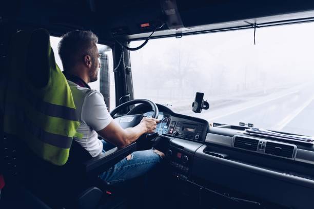 istock Handsome driver at the wheel of a truck at work. 1298420747