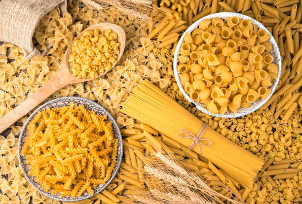 Wheat and lots of different kinds of pasta on the table Wheat and lots of different kinds of pasta on the table. The view from the top. Culinary background. The concept of food. carbohydrate food type photos stock pictures, royalty-free photos & images