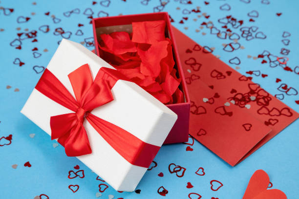 istock Box with ribbon filled with rose leaves on red envelope 1298423766