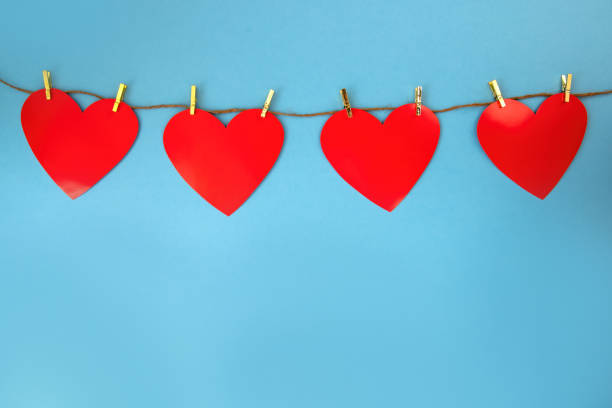 istock Four red hearts hanging on cord on blue background with copy space. 1298423937