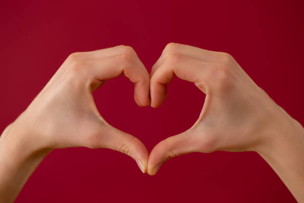istock Symbol of love made by two hands on red background 1298424197