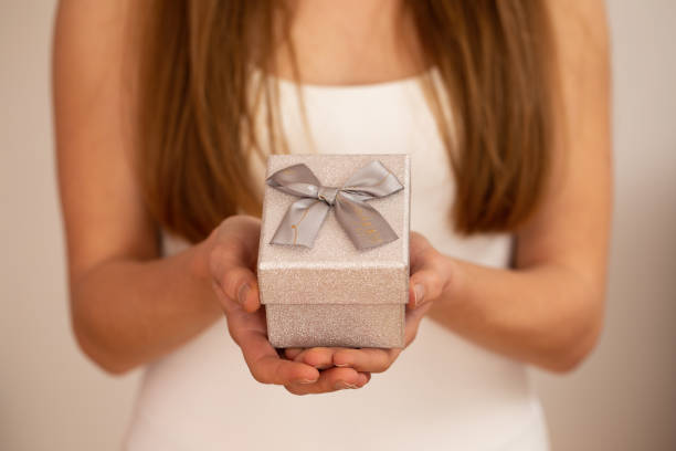 istock Woman holding little silver present with ribbon on white background 1298424738