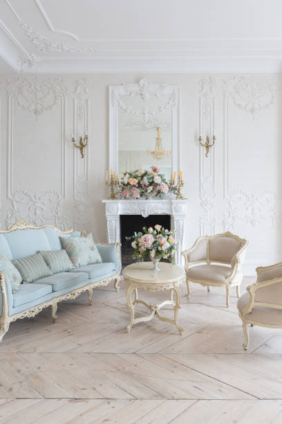 istock luxurious light interior in the Baroque style. A spacious room with a road chic beautiful furniture, a fireplace and flowers. plant stucco on the walls and light wood parquet 1298424778