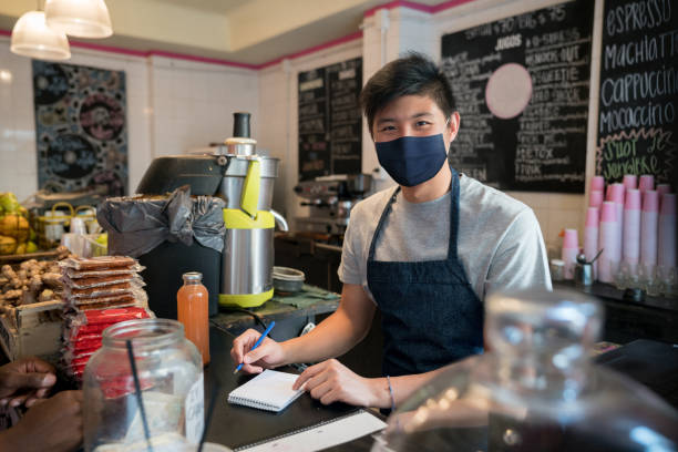 istock Asian man working at a  juice barwearing a facemask 1298425072