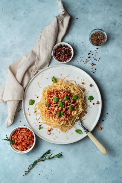 istock Classic bolognese with cheese and nuts in a flat plate, basil, spices and a light napkin on a gray background 1298428372