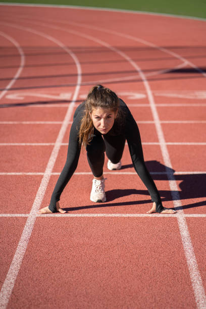 istock fit woman sprinter on a treadmill rubber stadium or running track getting ready to start run 1298428966