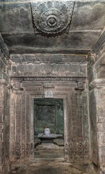 Lakkundi, Karnataka, India - November 6, 2013: Kasivisvesvara Temple. Looking through door into inner sanctum upon Shivalingam standing in Yoni. Gray stone walls, floor, and ceiling.
