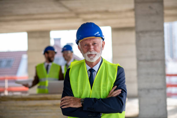 istock Senior man with arms crossed standing inside building structure. 1298429987
