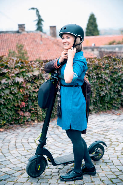 istock Woman on scooter tightens helmet 1298435553