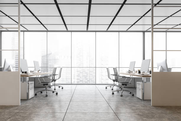 istock White office room with armchairs and computers on the tables near window 1298438013