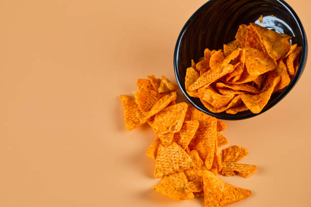 istock Bowl of crispy chips on orange background 1298439824
