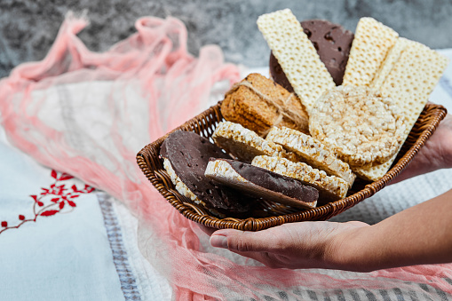 Hand holding a basket of mixed biscuits on a marble background. High quality photo