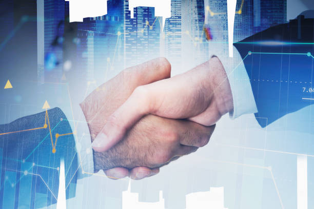 istock Two men shaking hands in city and graph 1298440277