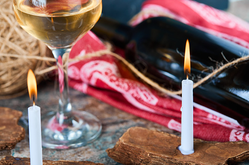 A glass of white wine and bottle with burning candles, close up. High quality photo