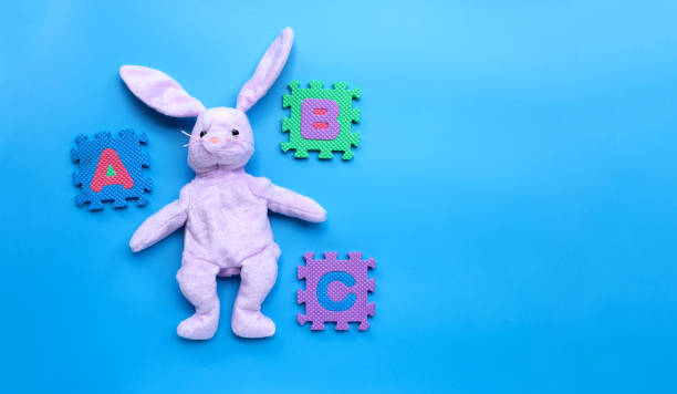 istock Rabbit toy with english alphabet puzzle on blue background. Education concept 1298441368