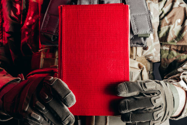 istock Soldier in uniform holding closed red book. 1298445007