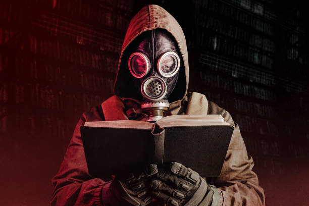 Stalker soldier in soviet gas mask holding opened old book. Photo of stalker soldier in soviet gas mask holding opened old book on dark background. weapons of mass destruction stock pictures, royalty-free photos & images